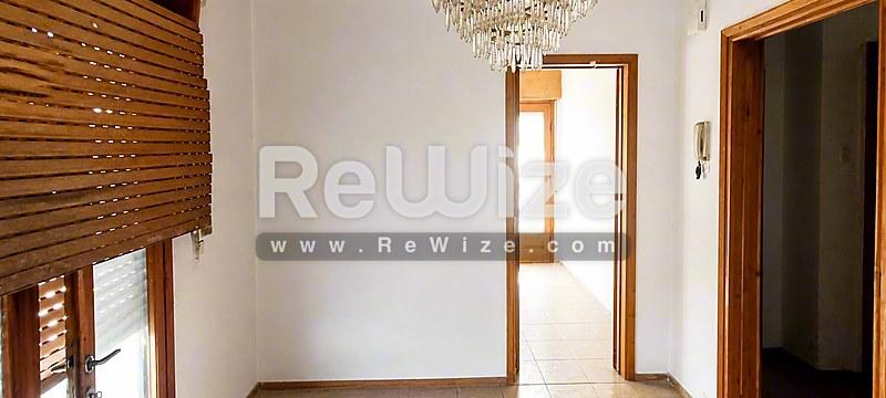 Φωτεινός διάδρομος σε διαμέρισμα της Χαλκιδικής με ξύλινες πόρτες και κρύσταλλο πολυέλαιο.