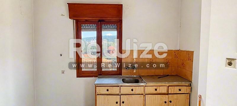 Συμπαγής κουζίνα διαμερίσματος στη Χαλκιδική με ξύλινα έπιπλα και θέα στα βουνά.