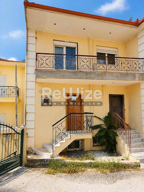 Κίτρινη μεζονέτα στη Χαλκιδική με διπλά μπαλκόνια και τερακότα διακόσμηση.