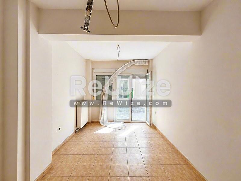 Φωτεινό σαλόνι μεζονέτας στη Χαλκιδική με τερακότα δάπεδο και γυάλινες πόρτες που ανοίγουν σε βεράντα.