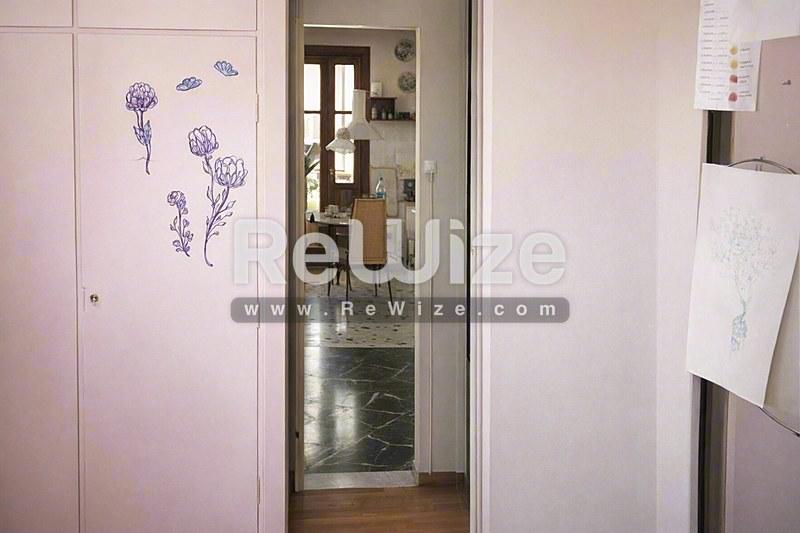 Δωμάτιο ενδυσίας ακινήτου στη Χαλκιδική με ροζ ντουλάπες, λουλουδάτη διακόσμηση και ανοιχτή πόρτα.