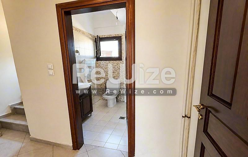 Φωτεινό μπάνιο σε μεζονέτα στη Χαλκιδική με τουαλέτα, νιπτήρα και πλακάκια.