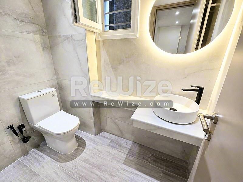 Σύγχρονο μπάνιο στην ιδιότητα Halkidiki rw-7585 με λευκές εγκαταστάσεις και φωτιζόμενο καθρέφτη.