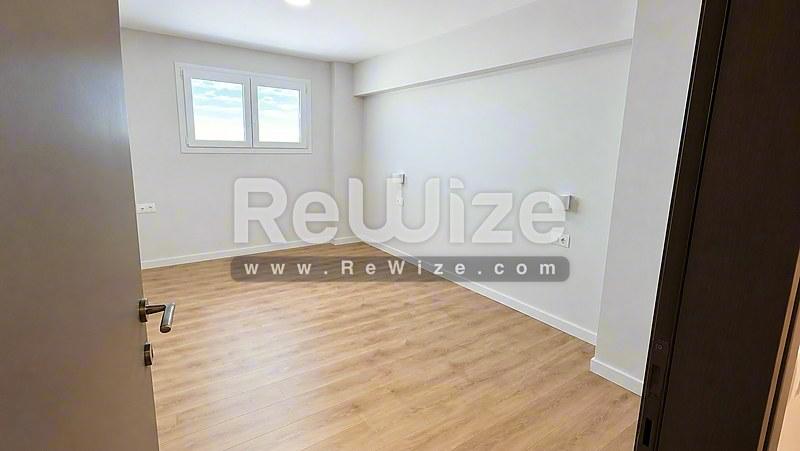 Φωτεινό υπνοδωμάτιο στο διαμέρισμα Halkidiki rw-7585 με ξύλινο δάπεδο και φυσικό φως από το παράθυρο.