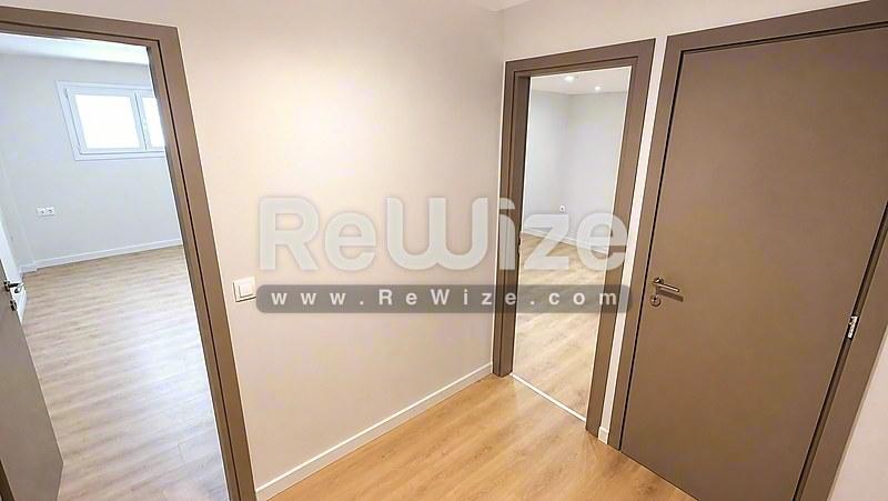 Φωτεινός διάδρομος του διαμερίσματος rw-7585 στη Χαλκιδική με ξύλινο δάπεδο και πολλές πόρτες.