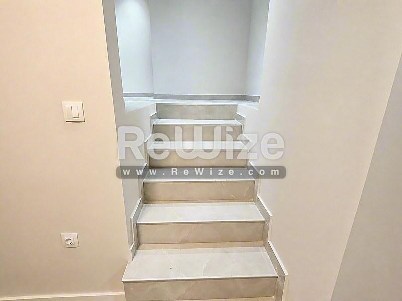 Φωτεινή σύγχρονη σκάλα στο ακίνητο rw-7585 στη Χαλκιδική με λευκούς τοίχους και ξύλινα σκαλοπάτια.
